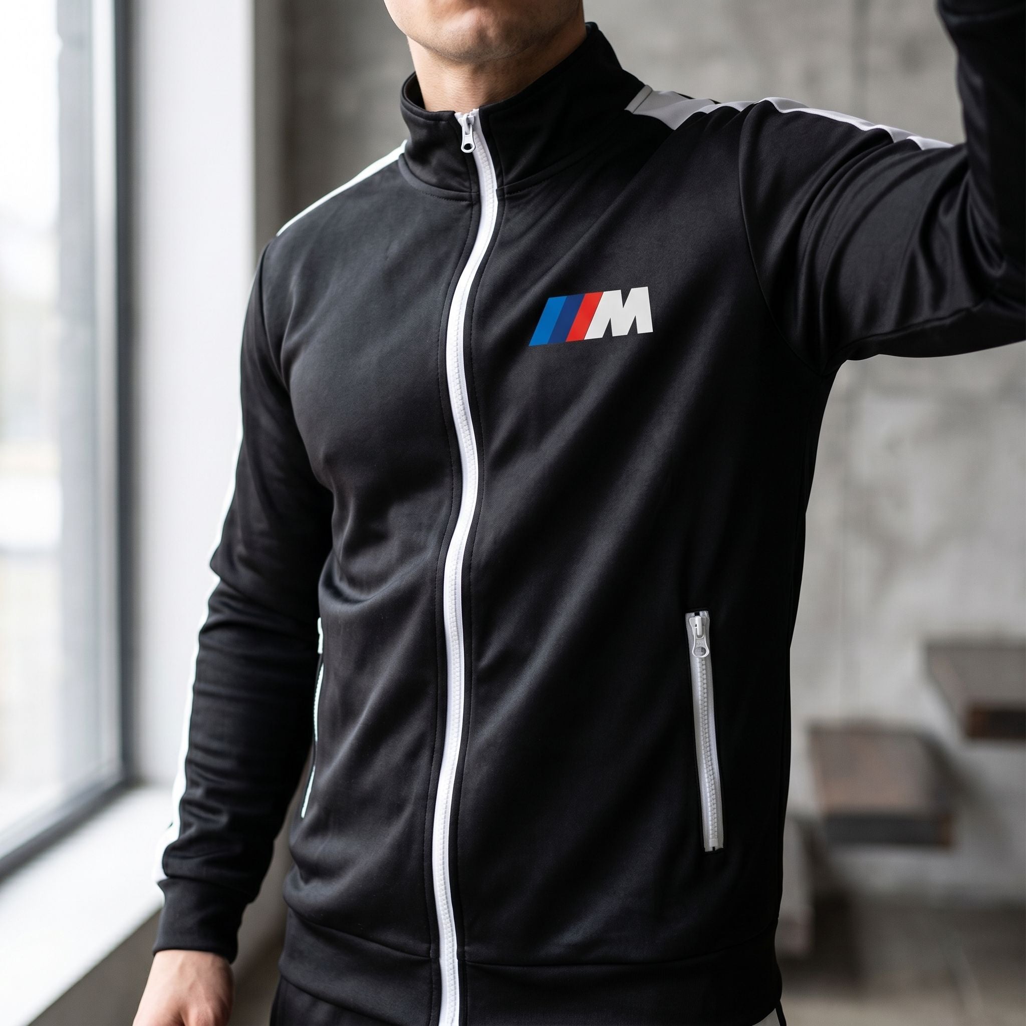 Close-up of male model's upper torso wearing BMW M Dri-Fit Track Suit in natural light, showcasing fit and material sheen in interior setting.