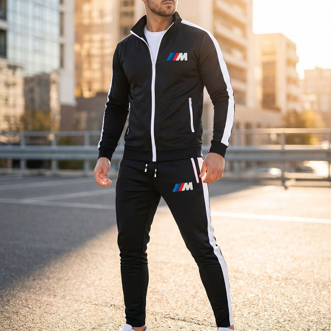 Male model wearing BMW M Dri-Fit Track Suit outdoors on sunny day with cityscape background, emphasizing sleek fit and fabric texture.