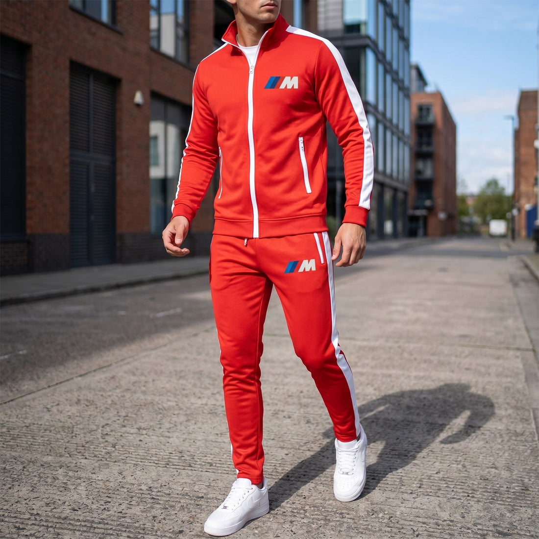 Full-body view of a man wearing black BMW M Dri-Fit TrackSuit on an urban street with cityscape background.
