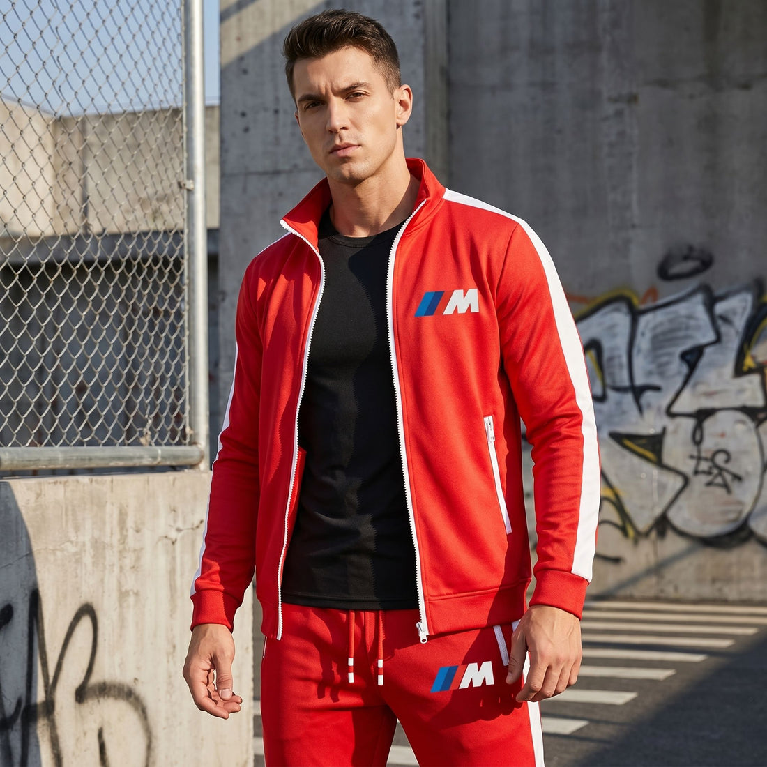 Model in BMW M Dri-Fit TrackSuit in urban training environment with graffiti and chain-link fence.
